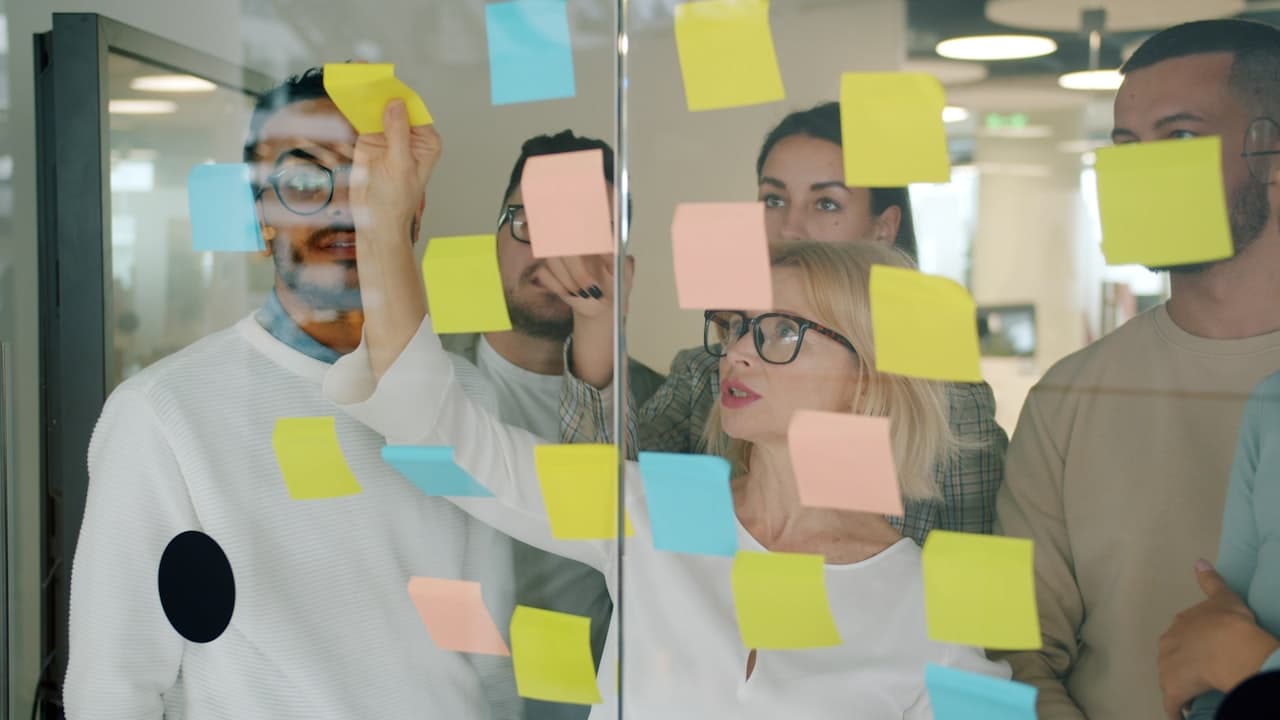 Équipe collaborant avec des notes sur un tableau de verre
