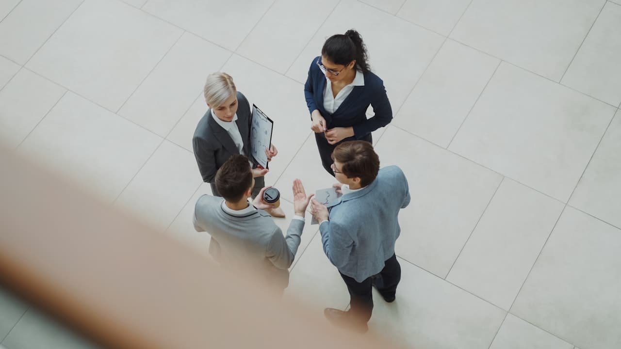 Quatre dirigeants en discussion dans un hall de bureau moderne