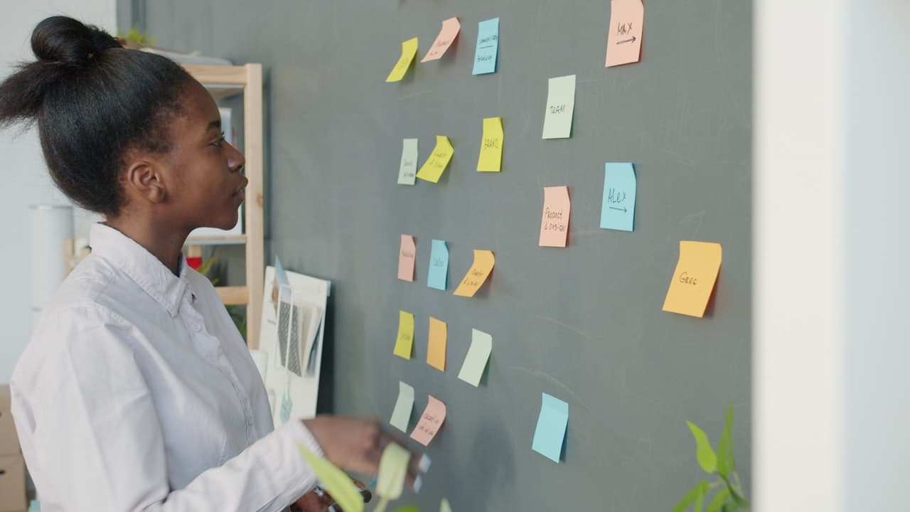 Femme consultant des notes de projet sur un mur de bureau