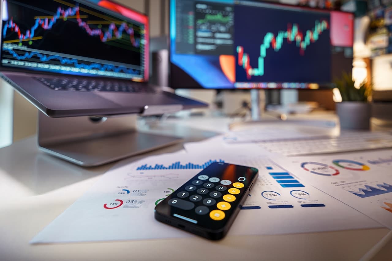 Smartphone calculatrice et graphiques financiers sur bureau