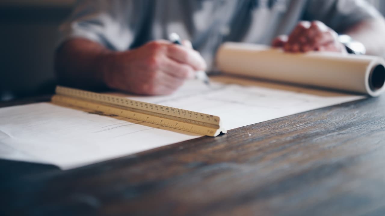 Personne dessinant des plans techniques sur papier