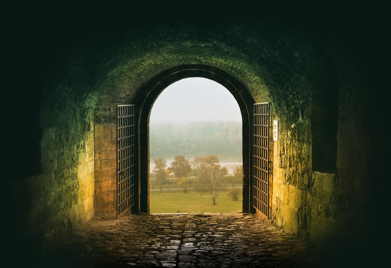 Tunnel sombre avec porte ouverte sur un champ lumineux