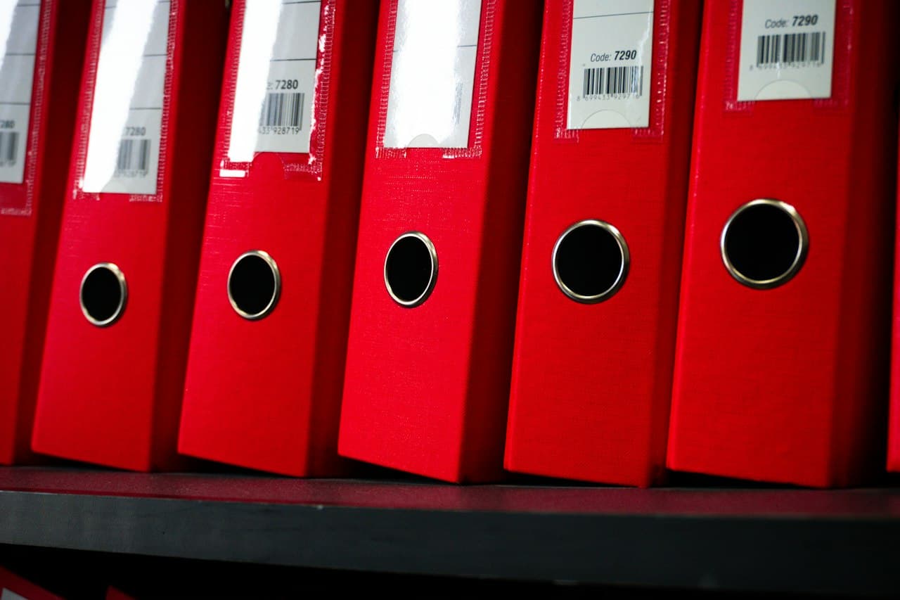 Dossiers rouges organisés sur une étagère de bureau