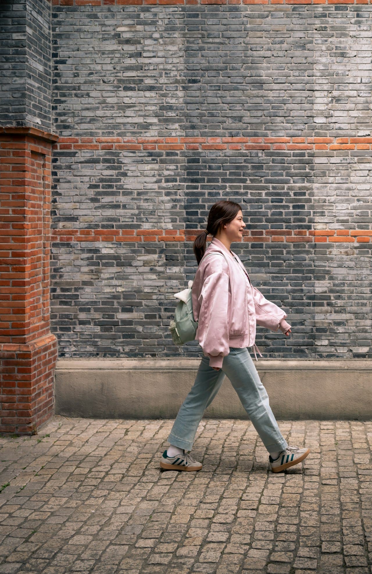 Femme avec sac à dos qui s'éloigne dans une rue urbaine