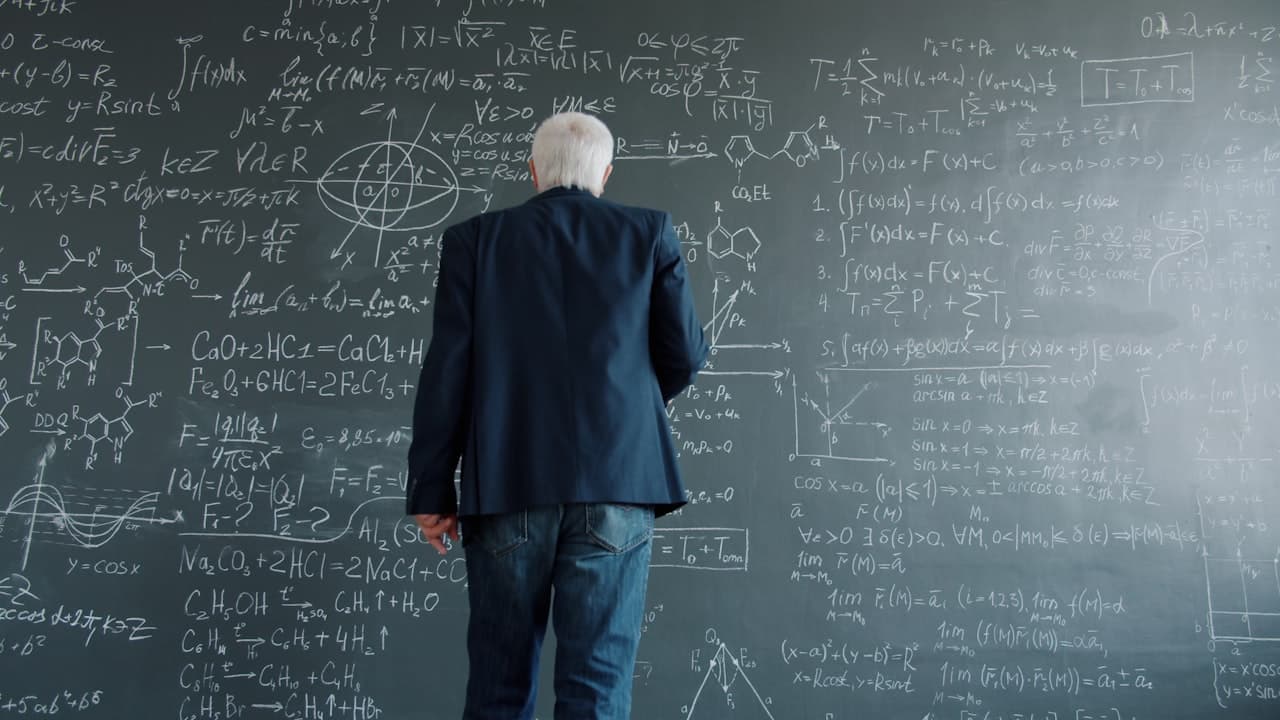 Professeur contemplant des équations mathématiques complexes au tableau